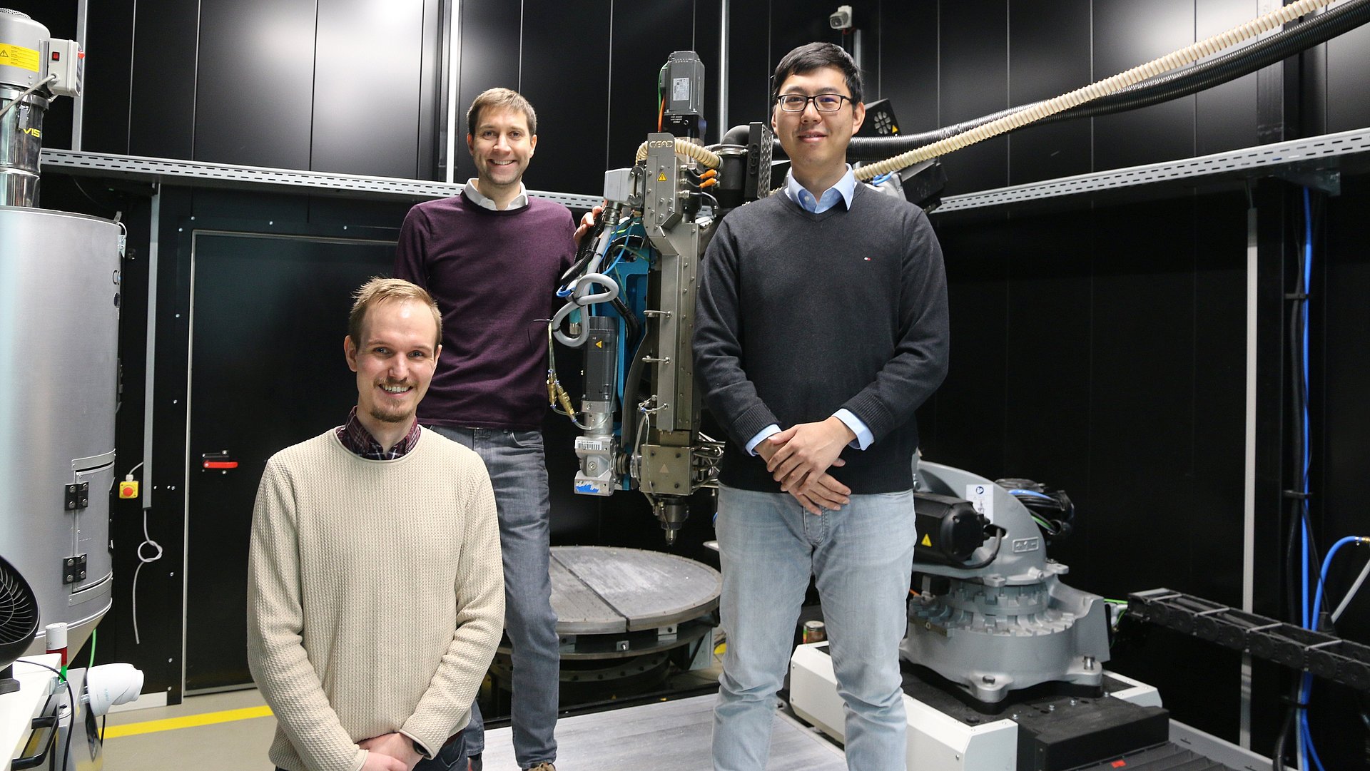 Die drei Gründende stehen um einen 3D-Drucker mit ihrer Technik.