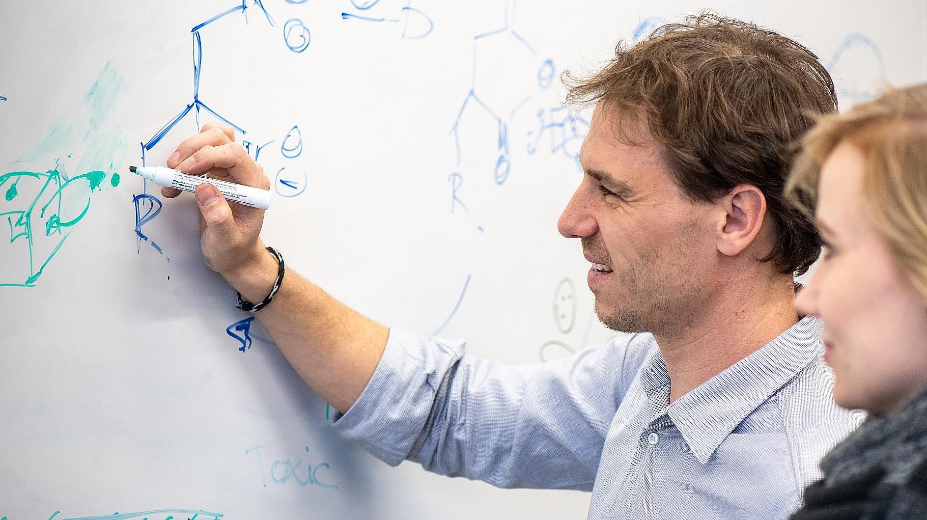 Prof. Job Boekhoven (l.) schreibt Strukturformeln an einem Whiteboard