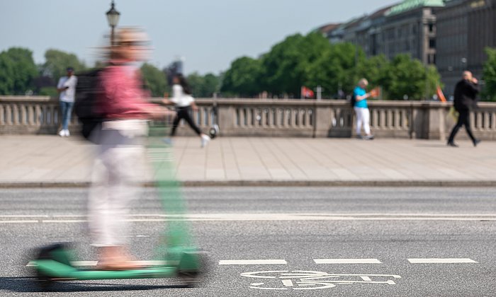  A person rides an e-scooter over a bridge