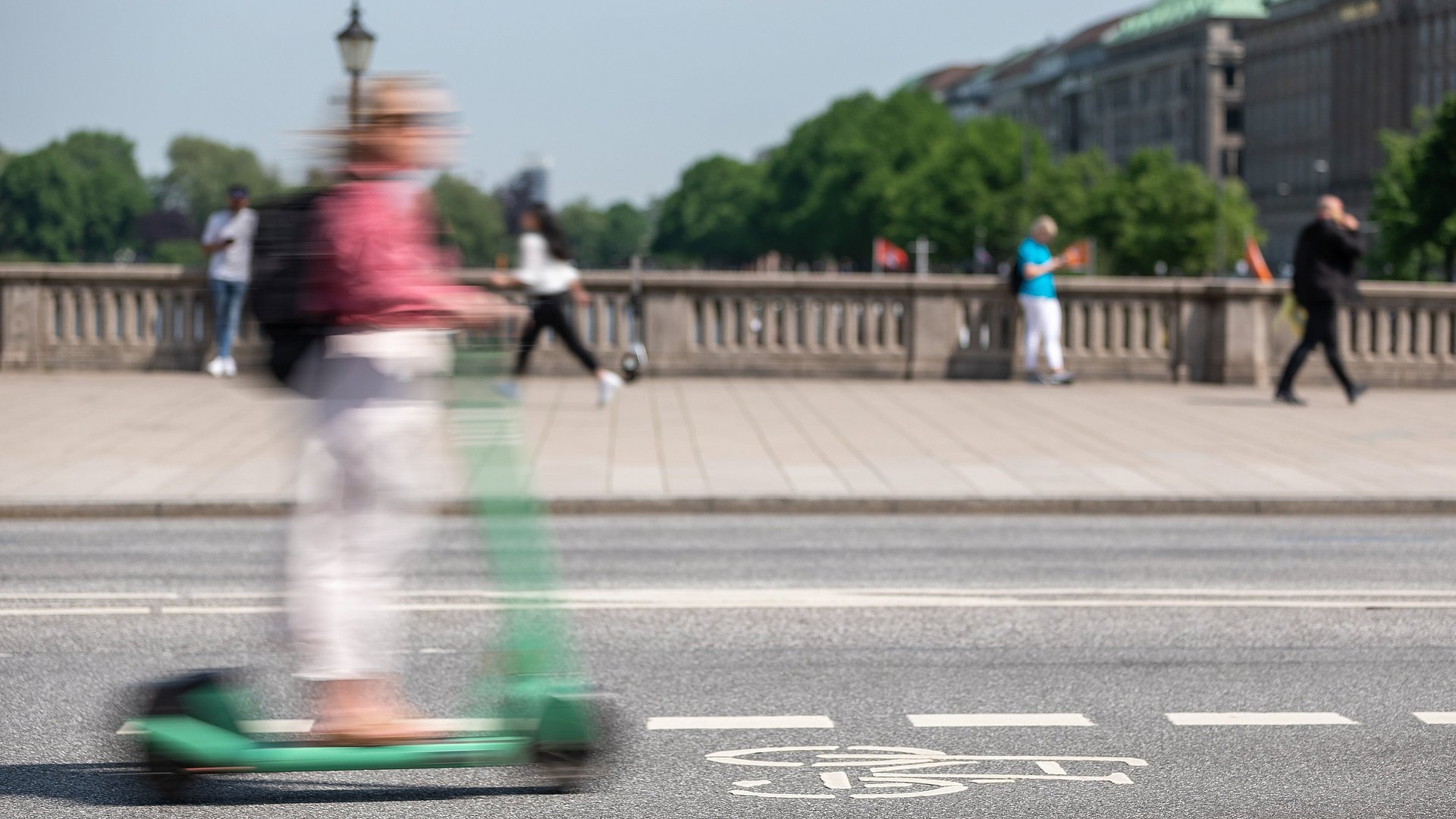  A person rides an e-scooter over a bridge