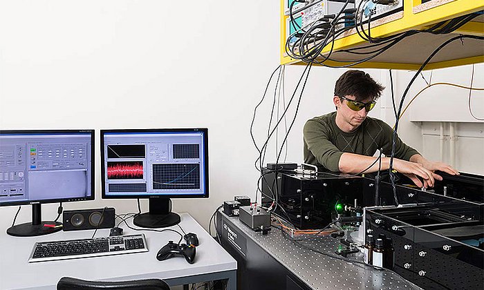 Mit einer „optischen Pinzette“ misst Marco Grison die Wechselwirkungen zwischen zwei Proteinen – Bild: Uli Benz / TUM