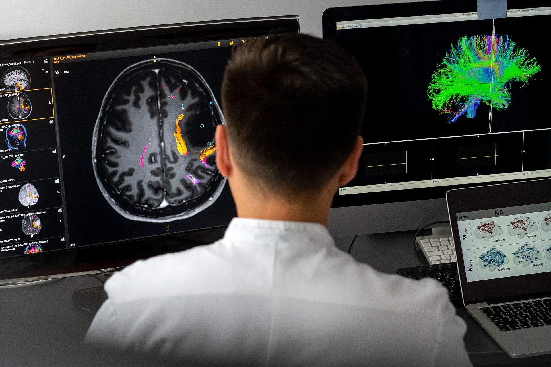 Forscher sitzt vor zwei Bildschirmen und macht eine 