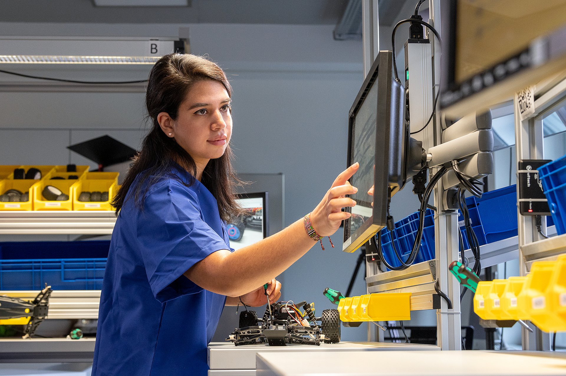 Woman operates digitized production processes via screen.