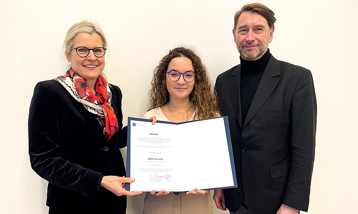 Standing from left Prof. Juliane Winkelmann (TUM), DAAD prizewinner Maria Elisa Magnoni, showing the award certificate, and Dr. Stephan Geifes (DAAD).