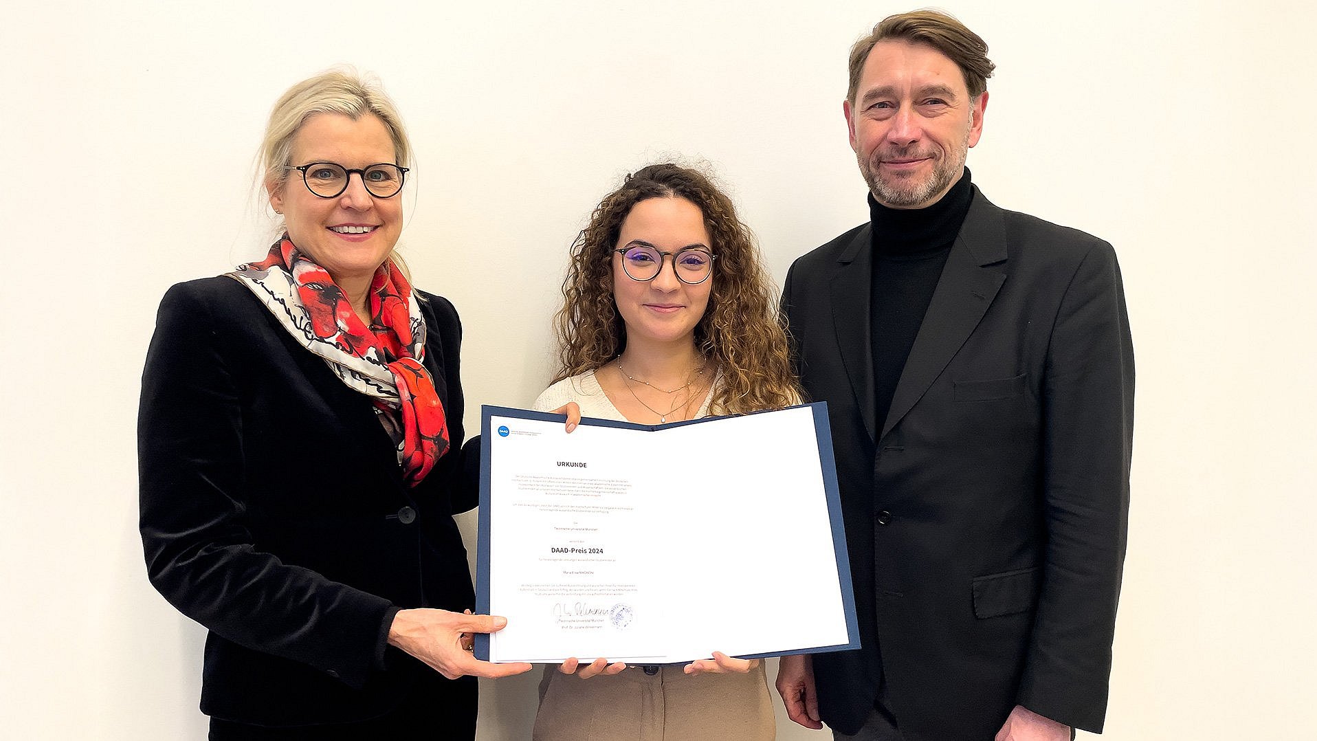 Standing from left Prof. Juliane Winkelmann (TUM), DAAD prizewinner Maria Elisa Magnoni, showing the award certificate, and Dr. Stephan Geifes (DAAD).