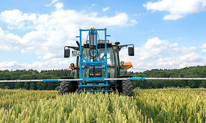Traktor im Getreidefeld mit vorne angebrachter Vorrichtung mit Sensoren.