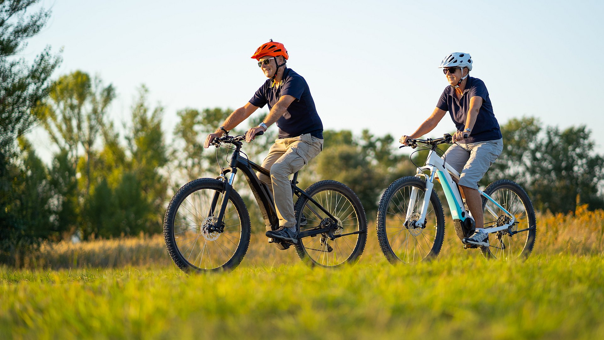 Two elderly people riding electric bikes
