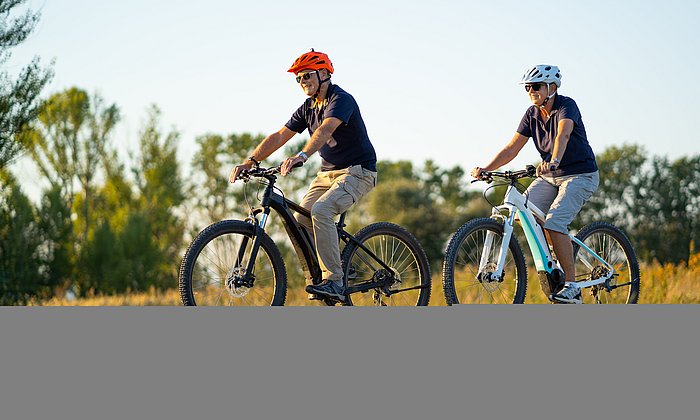 Zwei ältere Menschen fahren auf E-Bikes