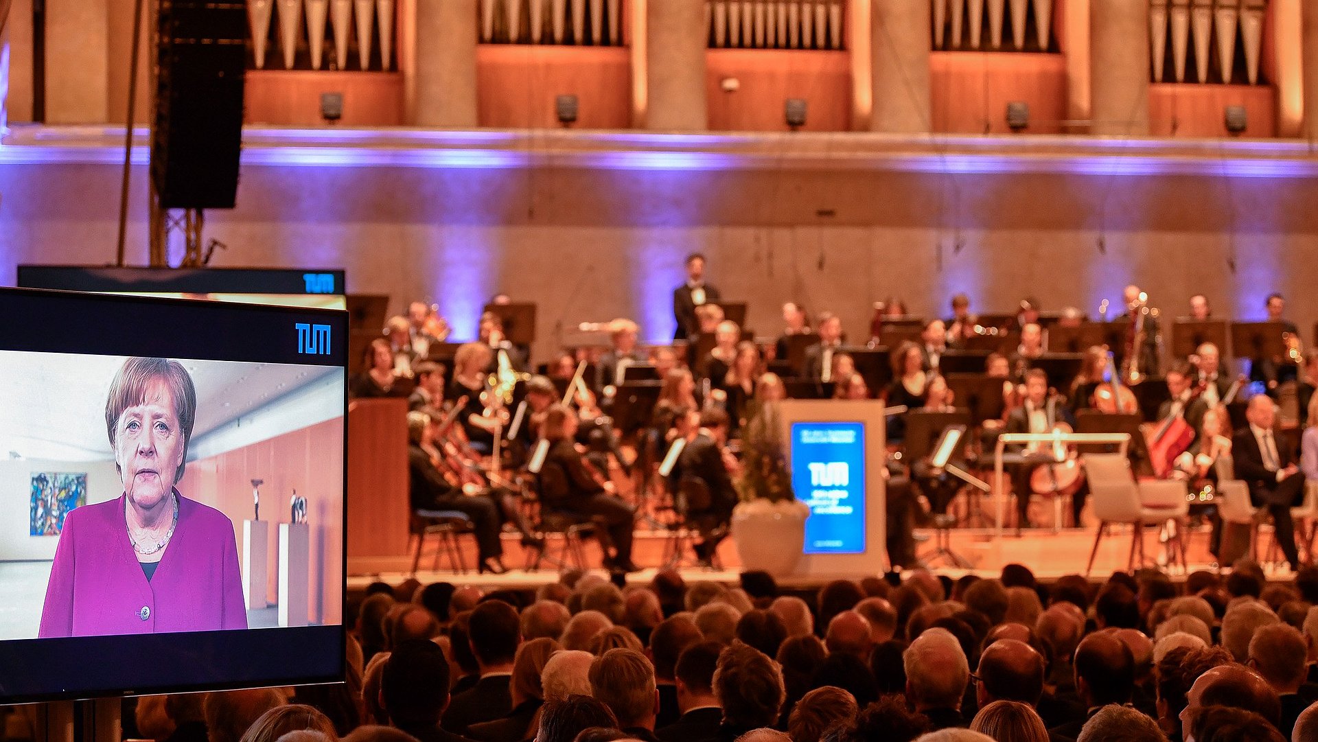 Angela Merkel live zugeschaltet auf einem Bildschirm. Sie spricht 2018 beim Festakt anlässlich des 150-jährigen Jubiläums der Technischen Universität München im Herkulessaal der Münchner Residenz.