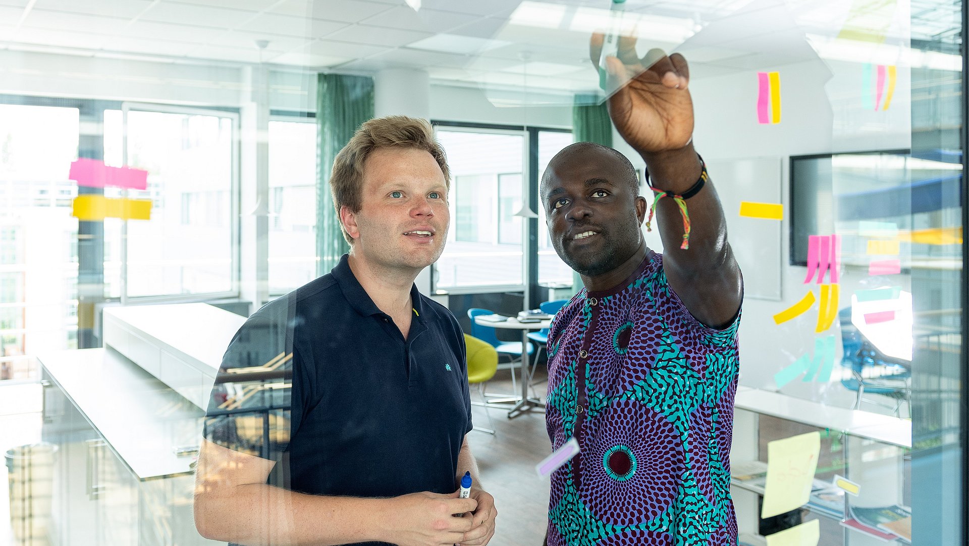 A young man explains something to another on a board.
