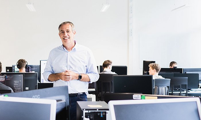Prof. Daniel Rückert mit anderen Personen in einem Arbeitsraum mit Computern.