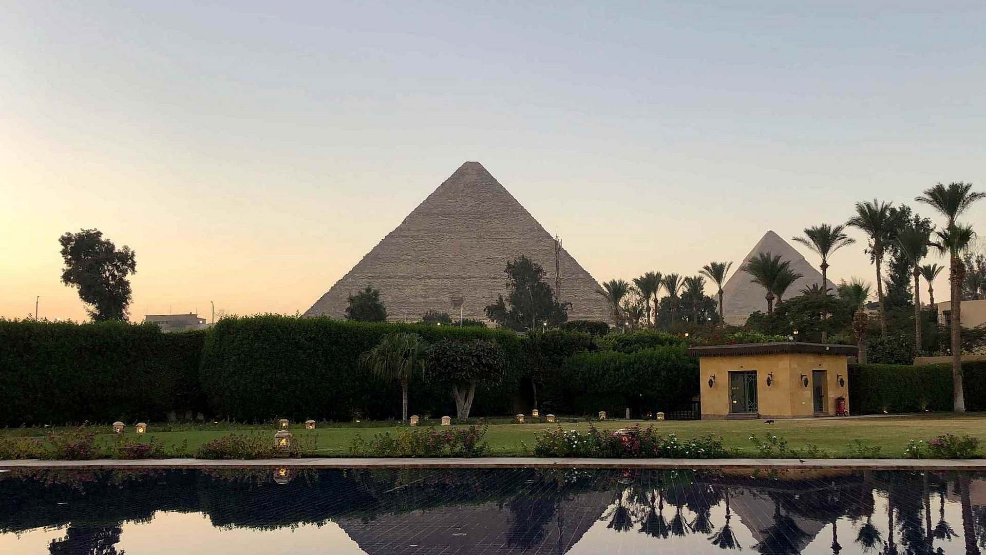 Cheops-Pyramide aus der Entfernung, im Vordergrund Palmen und Wasser