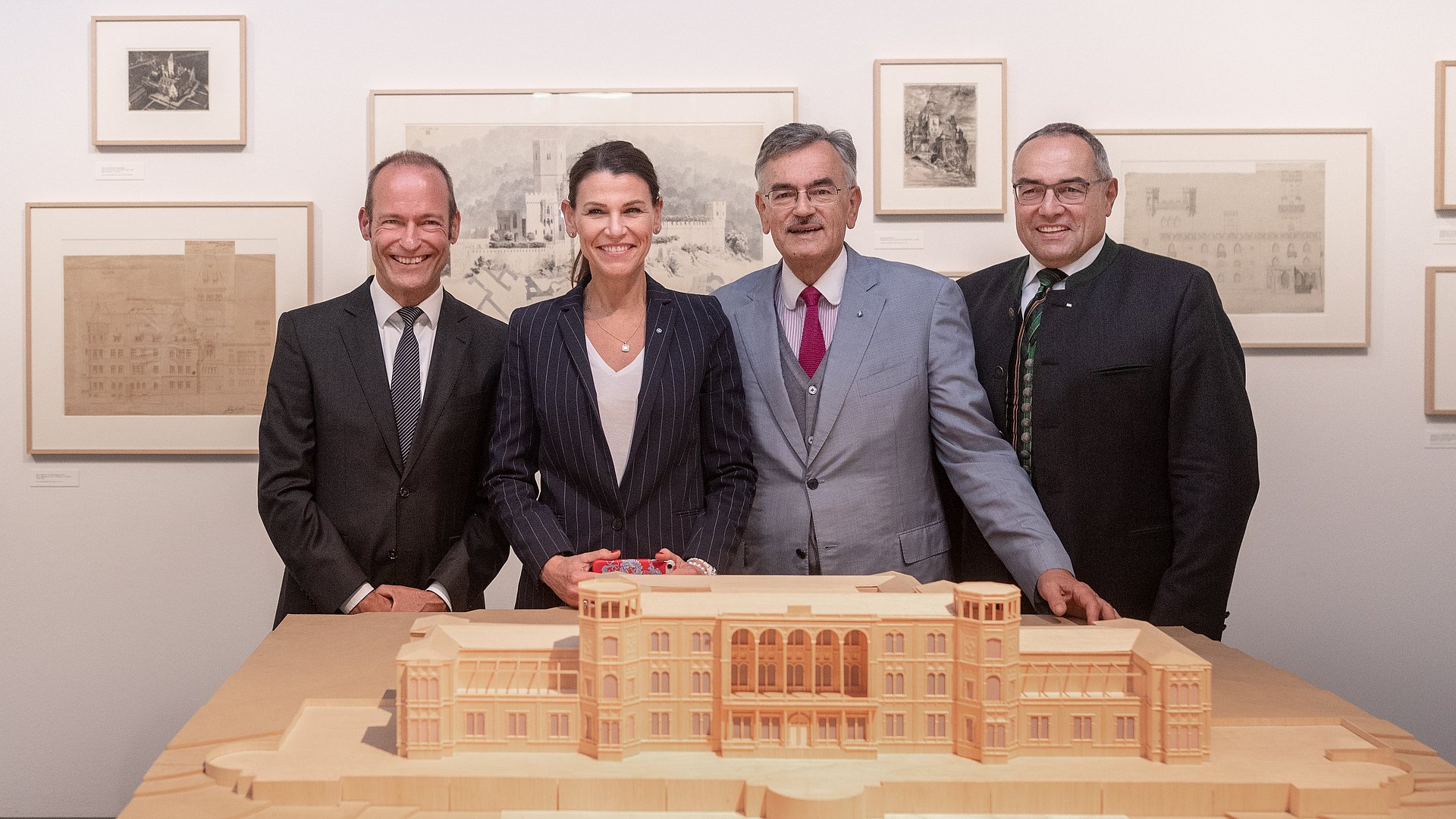 Prof. Dr. Andres Lepik, Professur für Architekturgeschichte und kuratorische Praxis sowie Direktor des Architekturmuseums, Prof. Marion Kiechle, 2018 Staatsministerin für Wissenschaft und Kunst, Präsident Emeritus Wolfgang A. Herrmann, im Jubiläumsjahr 2018 amtierender TUM-Präsident, und Kanzler Albert Berger stehen hinter einer Nachbildung eines historischen Gebäudes im Architekturmuseum.