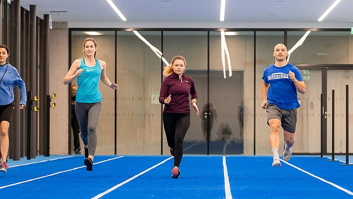Vier Stueirende sprinten in einer der größten neuen Sporthallen.