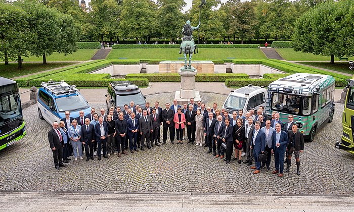 Teilnehmende des IAA Roundtable „Modellregionen für Autonomes Fahren im ÖPNV“  im Hof der Staatskanzlei vor autonom fahrenden Fahrzeugen