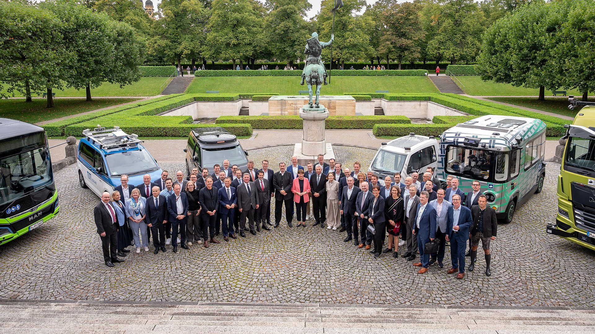Teilnehmende des IAA Roundtable „Modellregionen für Autonomes Fahren im ÖPNV“  im Hof der Staatskanzlei vor autonom fahrenden Fahrzeugen