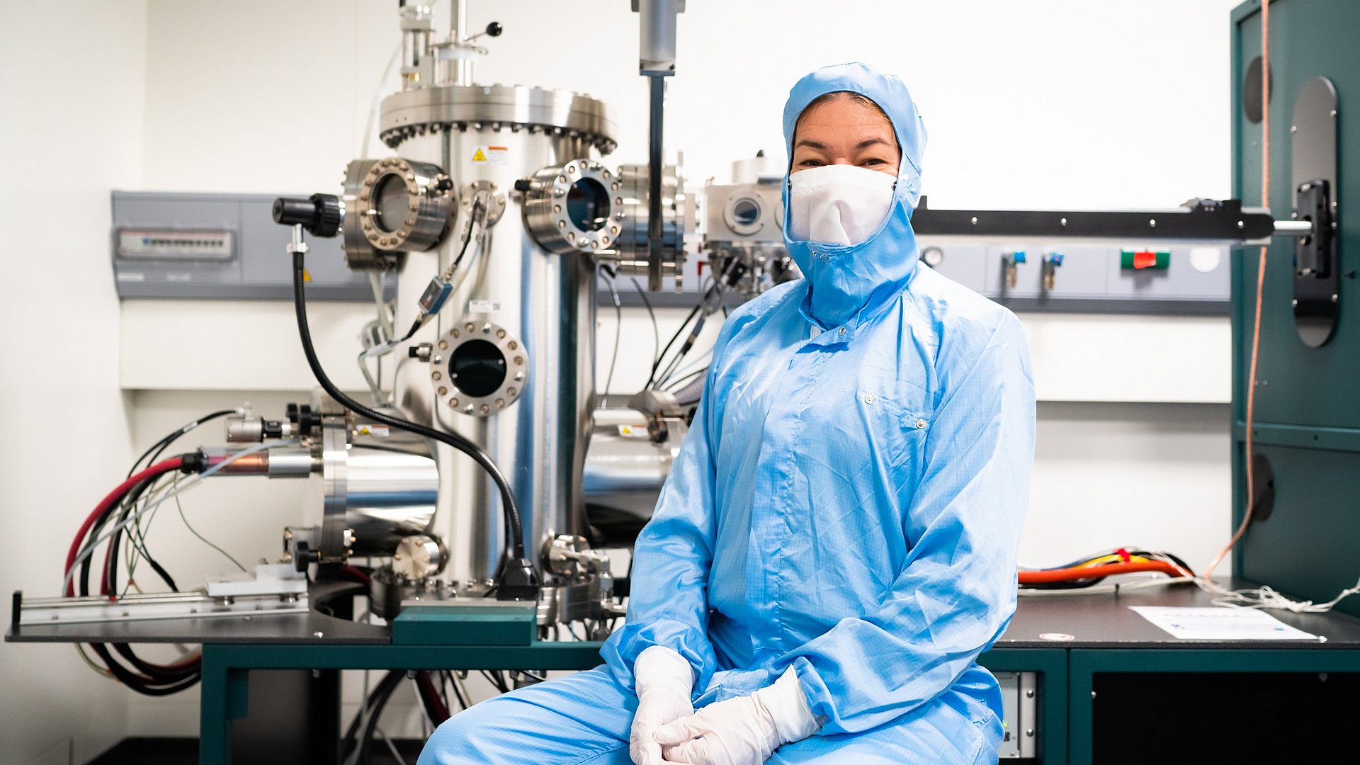 Die Professorin Eva Weig vor der Apparatur zum Aufdampfen der verschiedenen metallischen Schichten auf die Chips.