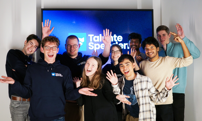Eine Gruppe Studierender vor dem Logo von Talente Spenden e.V.