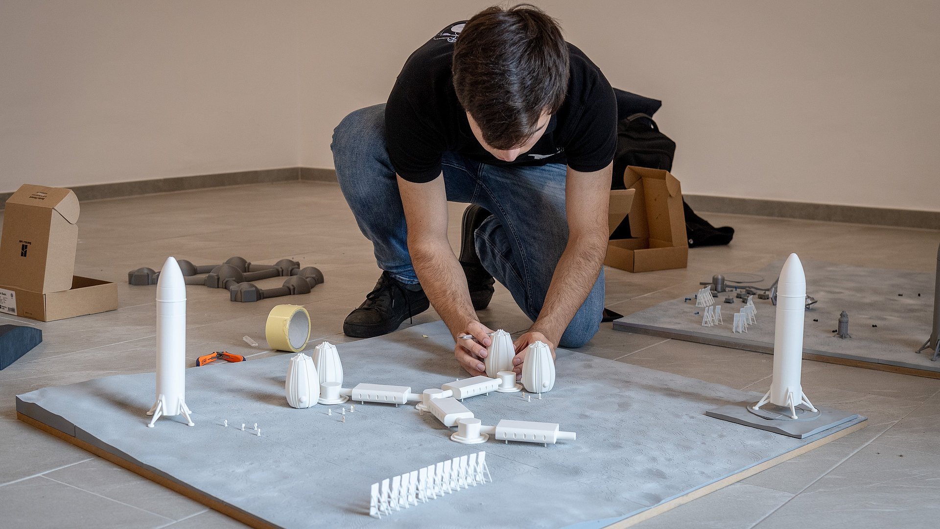 Student glues parts of a lunar settlement from the 3D printer onto a lunar landscape