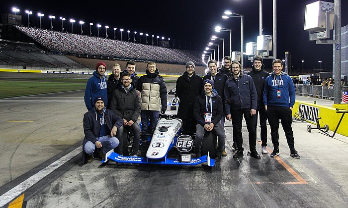 Eine Gruppe Wissenschaftler:innen stehen um einen Formel-Rennwagen.