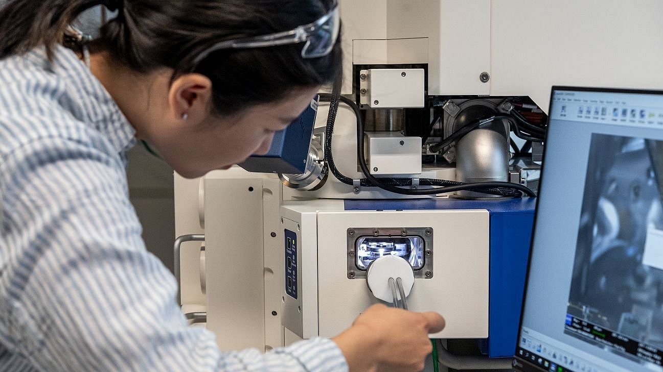 Yixiao places a sample in the microscope.