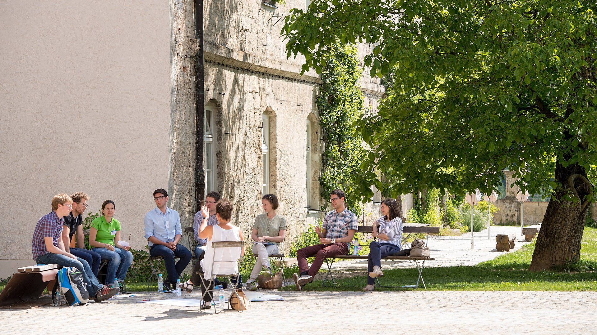 People are sitting in a circle in the academy gardens.