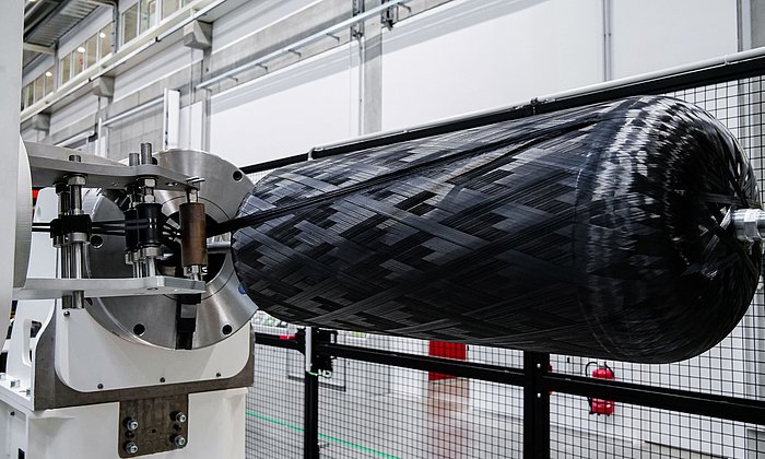 Ein Drucktank wird mit Carbonfasern in einer Fertigungshalle gewickelt.