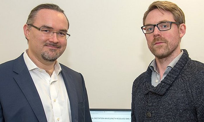 Prof. Dr. Juergen Hauer (li) und Erstautor Erling Thyrhaug mit ihrem Messinstrument. Im Hintergrund Spektren, die damit aufgenommen wurden. (Bild: A. Battenberg / TUM)