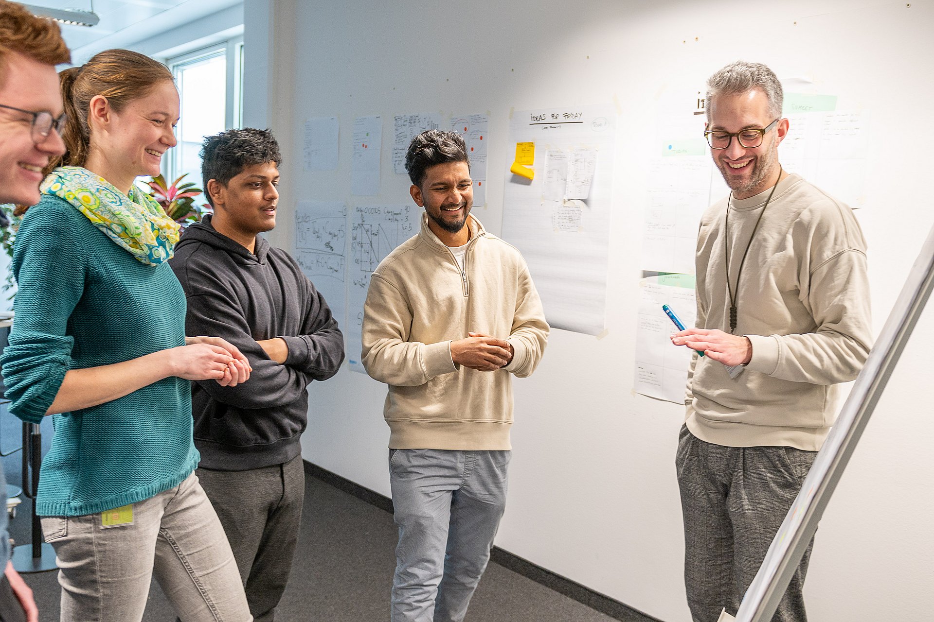 Four students look at a display. The team leader stands next to the display and explains what can be seen.