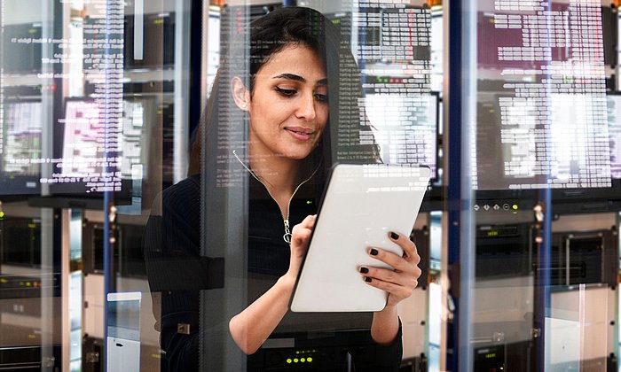 Eine Frau mit Tabelt in einem Rechenzentrum.