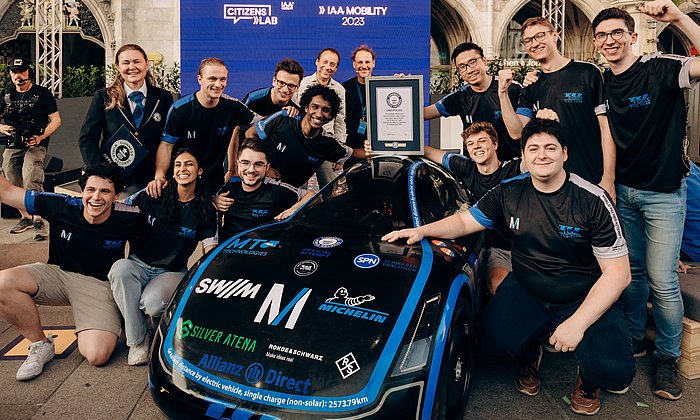 Studierende stehen um ein Versuchsfahrzeug herum und feiern ihren Sieg.