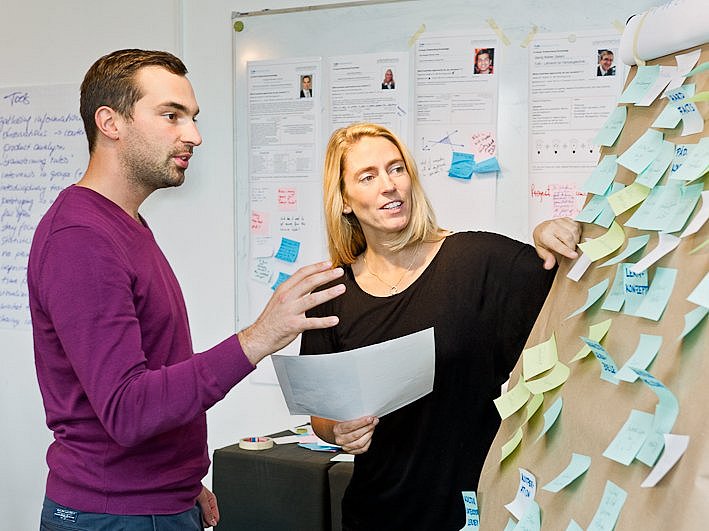 Zwei Personen unterhalten sich vor einem Flipchart.