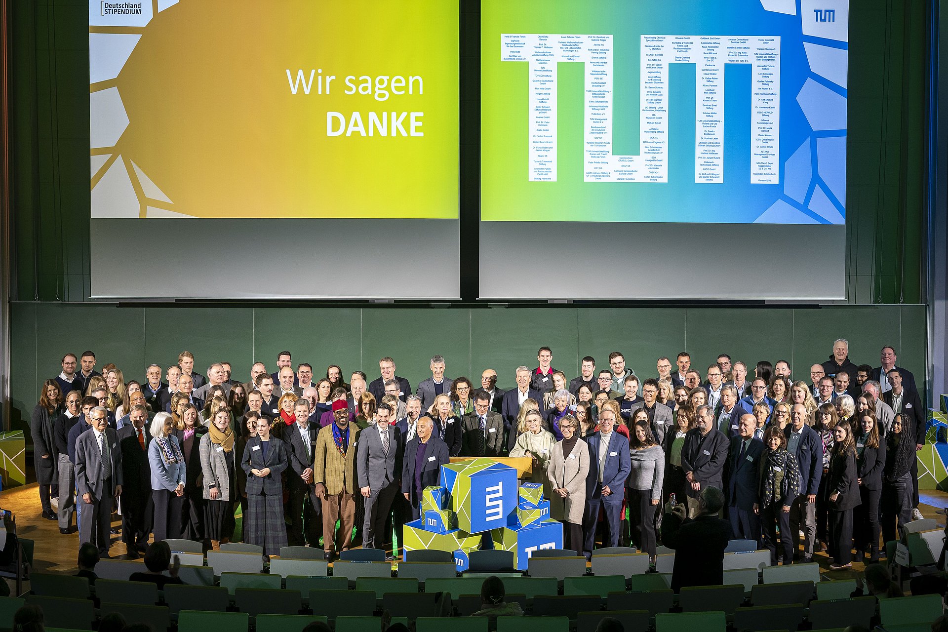 Gruppenfoto mit allen Förderern des Deutschlandstipendiums an der TUM bei der Festveranstaltung. Sie stehen auf der Bühne. 