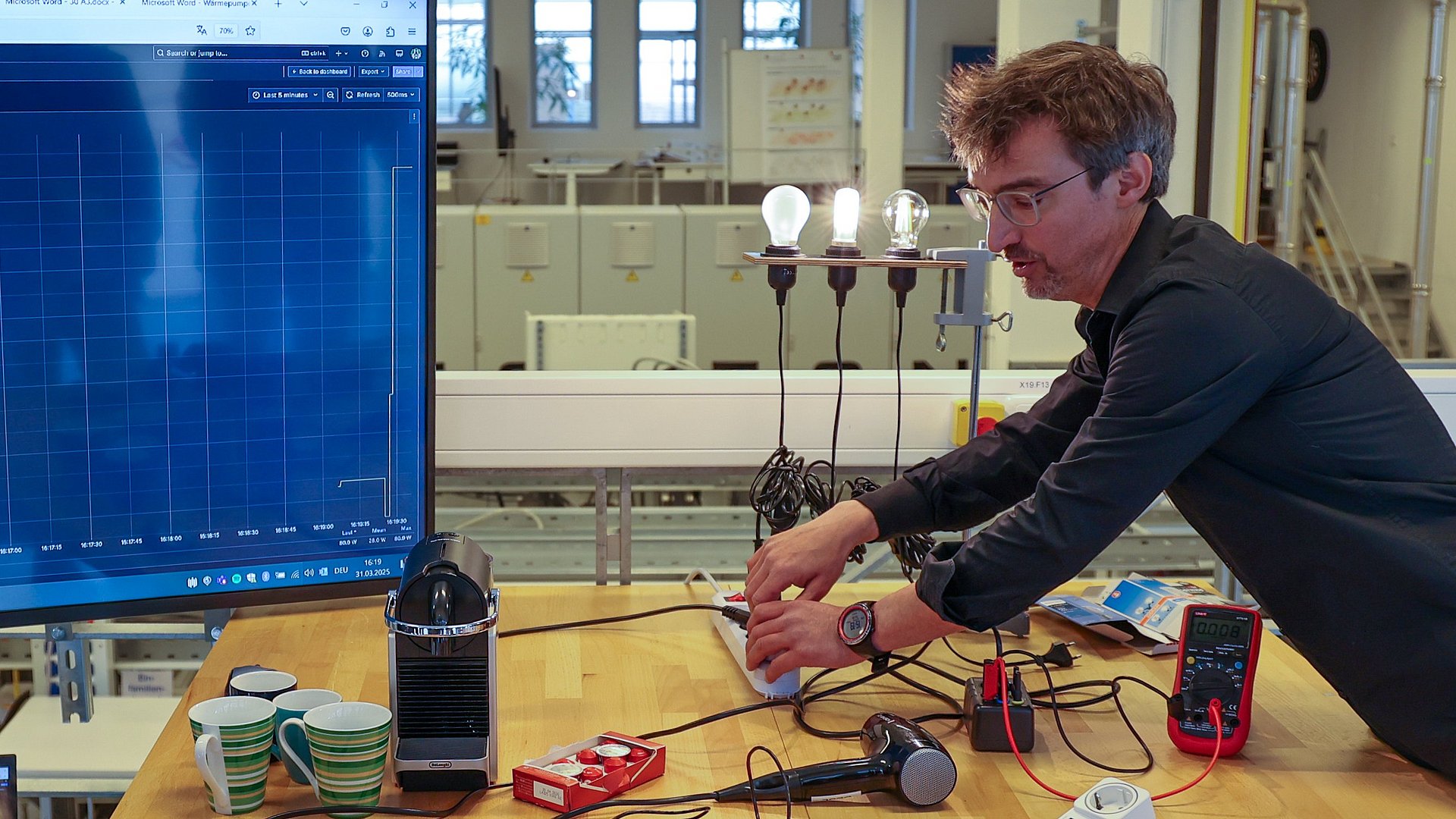 Forschender misst den Energieverbauch von unetrschiedlichen Lampen.