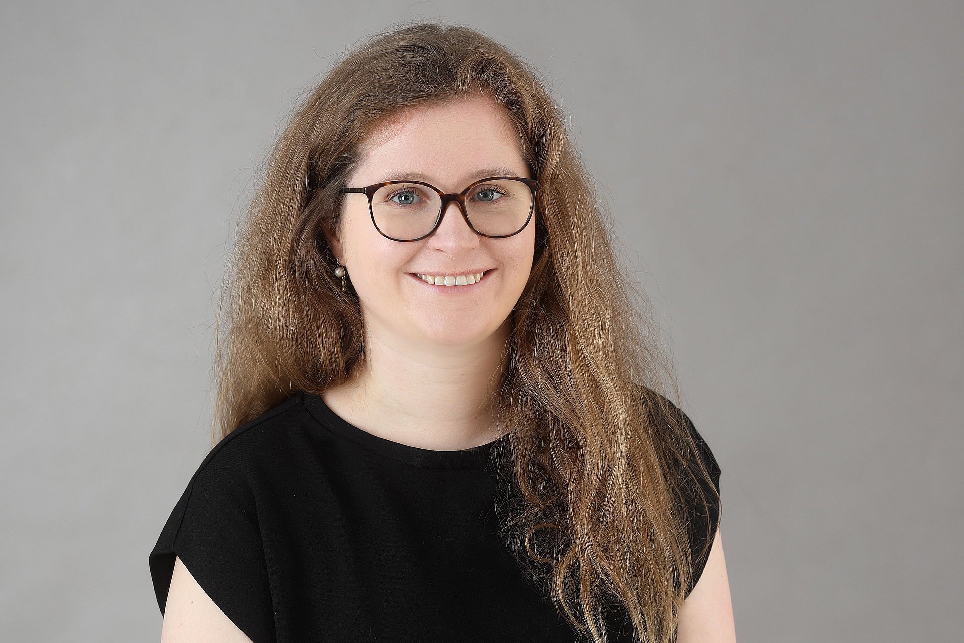 Frau mit Brille und langen Haaren schaut freundlich in die Kamera