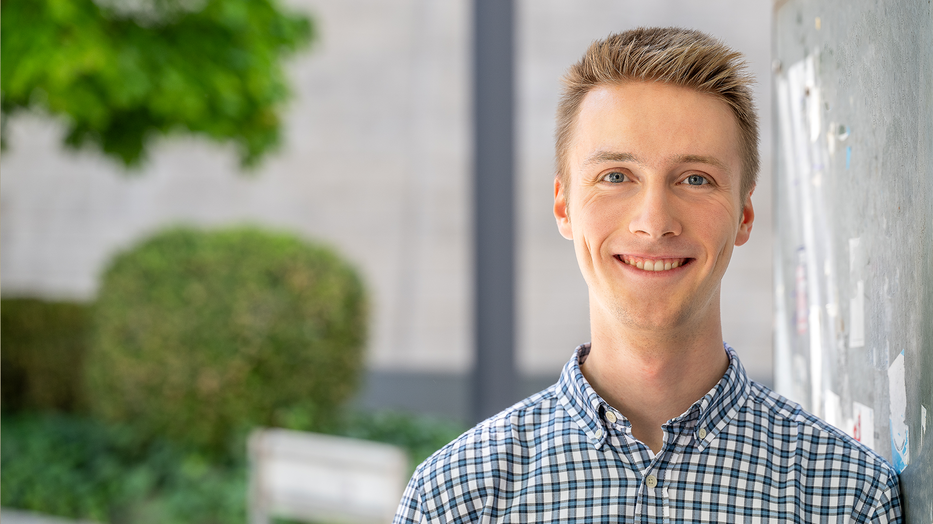 Junger Mann mit kurzem blonden Haar lächelt freundlcih in die Kamera. Er ist Stipendiat
