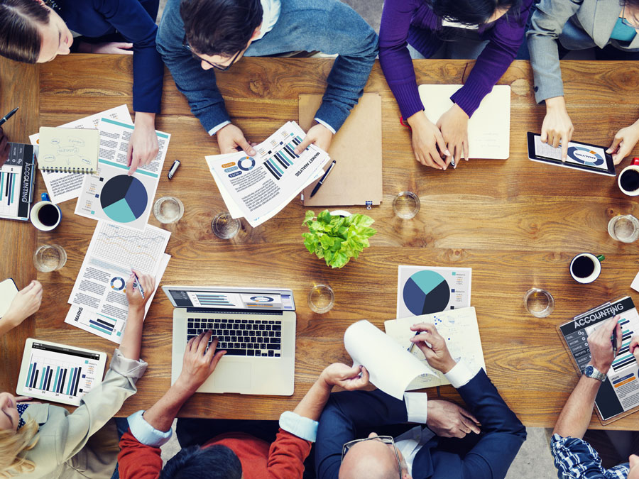 Mitarbeiterinnen und Mitarbeiter eines Unternehmens diskutieren an einem Tisch.